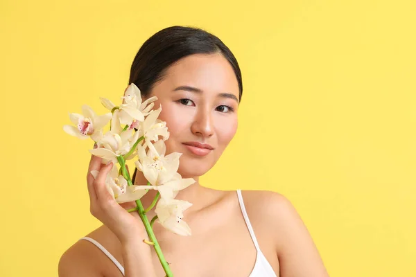 Junge Frau Mit Orchideenblüten Auf Farbigem Hintergrund — Stockfoto
