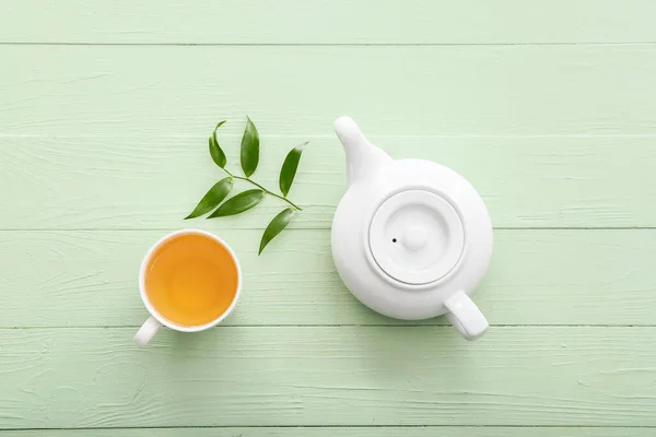 Teekanne Und Tasse Tee Mit Grünen Blättern Auf Farbigem Holzhintergrund — Stockfoto