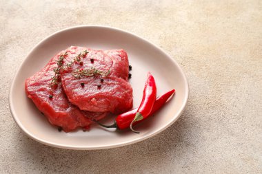 Plate with raw beef meat on light background