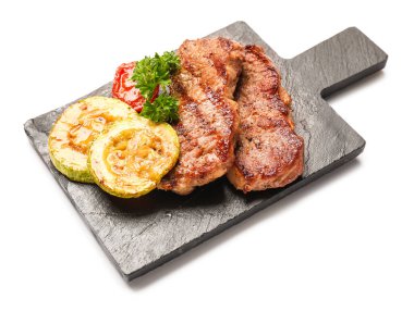 Board with tasty beef steaks and grilled vegetables on white background