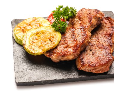 Board with tasty beef steaks and grilled vegetables on white background, closeup