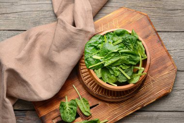 Tahta arka planda taze ıspanak yapraklı kase