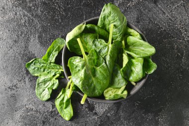 Koyu arkaplanda taze ıspanak yaprakları olan kase.