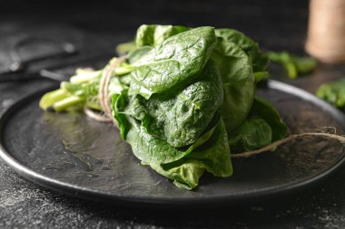 Koyu arka planda taze ıspanak yapraklı tabak, yakın plan.
