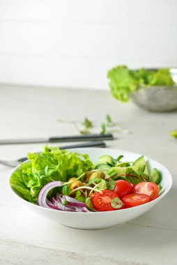 Beyaz ahşap masada sebzeli taze salata.
