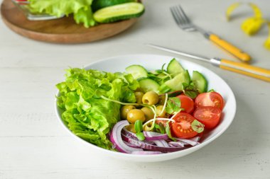 Beyaz ahşap masada sebzeli taze salata.