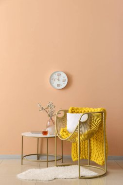 Koltuk ve vazo renkli duvarın yanındaki masada çiçek açan dallar.