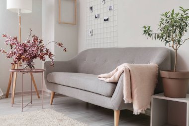 Oturma odasının içindeki masada çiçek açan dalları olan vazo.