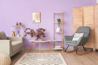 Şık oturma odasının içinde çiçek açan dalları olan bir vazo.