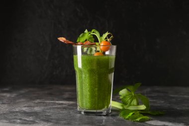 Arka planda pastırmayla süslenmiş bir bardak Bloody Mary kokteyli.