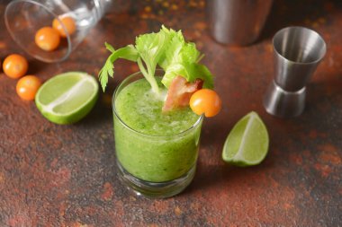 Arka planda domuz pastırması ile süslenmiş bir bardak Bloody Mary kokteyli.