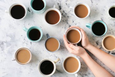 Kadın eli ve kahve fincanları arka planda.