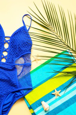 Renkli arka planda şık mayo, havlu ve palmiye yaprağı kompozisyonu, yakın plan