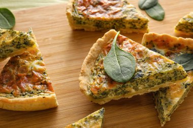 Ahşap arka planda lezzetli ıspanaklı tart parçaları, yakın plan.