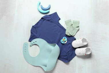 Bebek kıyafetleri, ayakkabıları, önlüğü ve emziği olan kompozisyon