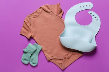 Renkli arka planda bebek kıyafetleri ve önlüğü