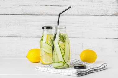 Hafif ahşap arka planda salatalıklı limonata şişeleri