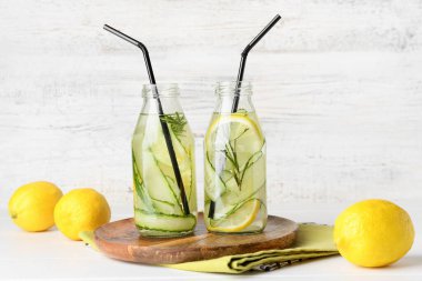 Hafif ahşap arka planda salatalıklı limonata şişeleri