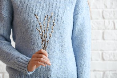 Tuğla duvarın yanında söğüt dalları tutan kadın, yakın çekim