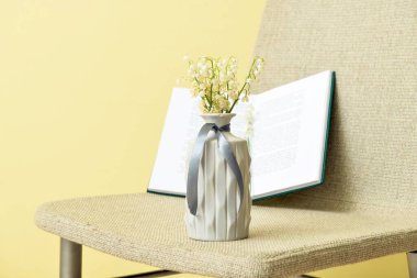 Vadideki güzel çiçekli vazo renkli duvarın yanındaki sandalyede.