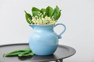 Vadi zambağı çiçekli vazo ışıklı duvarın yanındaki masada.