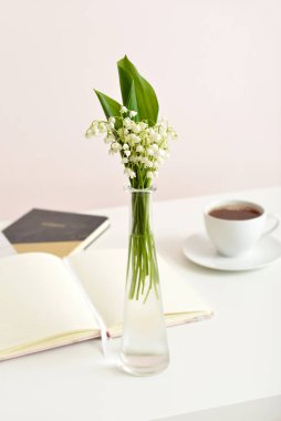 Vadi zambağı çiçekli vazo ve masada kitaplar.
