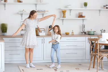 Genç kadın ve küçük kızı mutfakta dans ediyorlar.