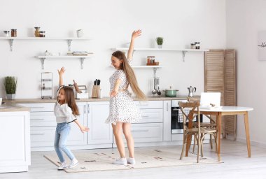 Genç kadın ve küçük kızı mutfakta dans ediyorlar.