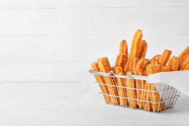 Hafif ahşap arka planda parşömende lezzetli churros sepetleri.