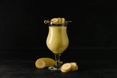 Glass of tasty banana daiquiri cocktail and fruits on wooden table