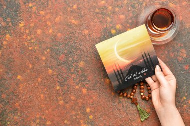 Kurban Bayramı için tebrik kartı taşıyan kadın eli (Kurban Bayramı), Türk çayı ve renkli fonda tasbih