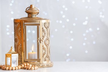 Muslim lanterns with tasbih on light background