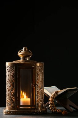 Muslim lantern with Quran and tasbih on dark background