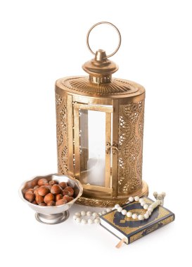Muslim lantern with Quran, tasbih and nuts on white background