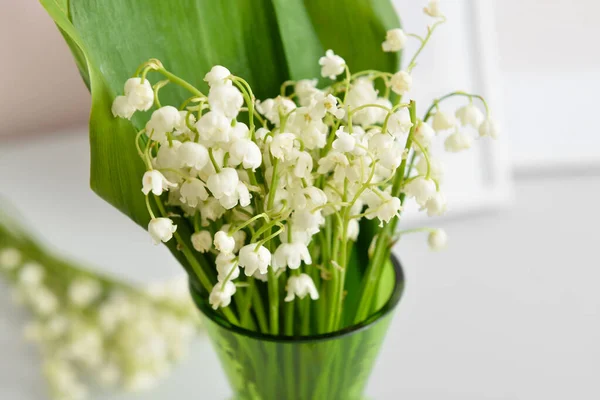 Vase with lily-of-the-valley flowers on shelf, closeup