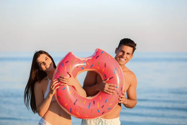 幸せな若いですカップルともにインフレータブルリングオン海ビーチ — ストック写真