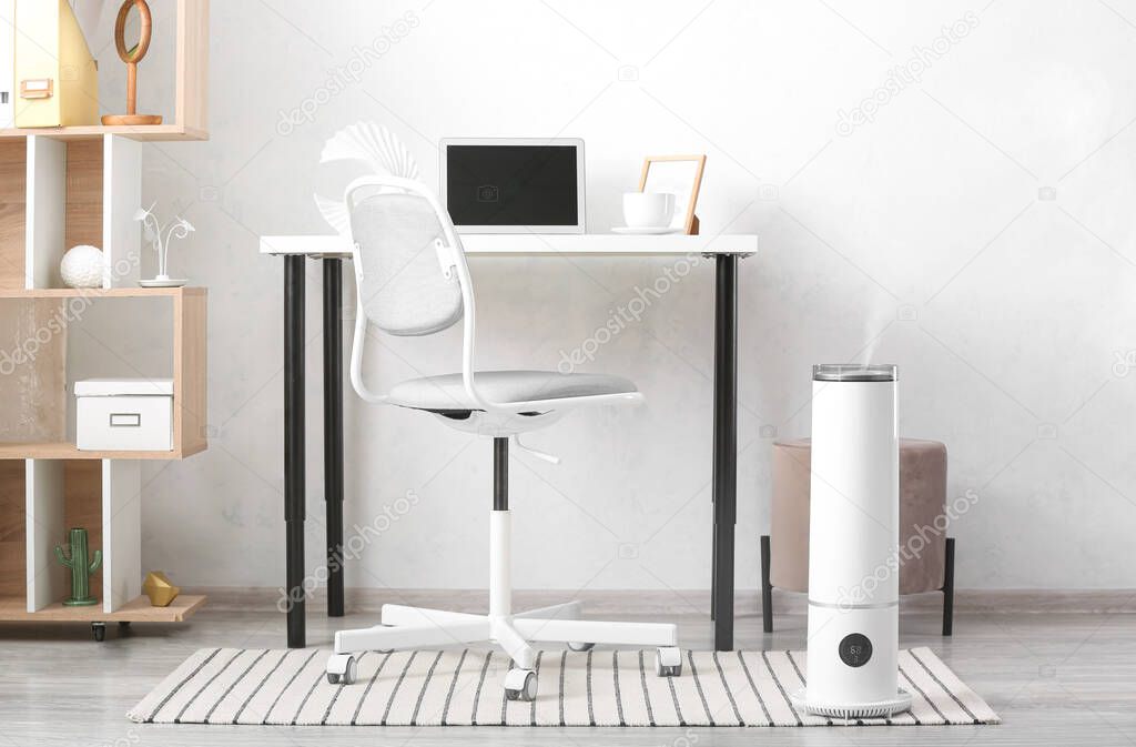 Interior of room with modern humidifier and comfortable workplace