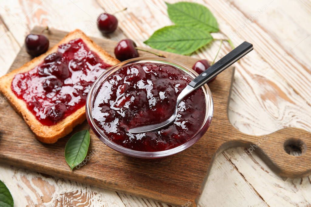 Bowl and toast with cherry jam on wooden background
