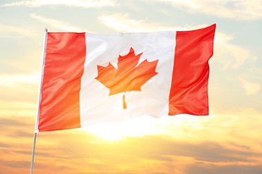 Kanada 'nın ulusal bayrağı gün batımında bulutlu gökyüzüne karşı