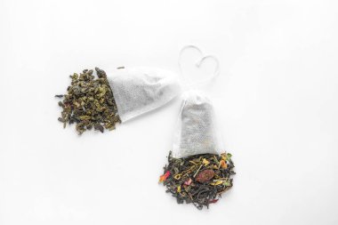 Beyaz arka planda kuru yapraklı çay poşetleri