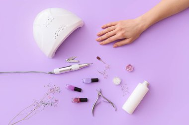 Renk arkaplanındaki manikür için kadın eli ve profesyonel araçlar