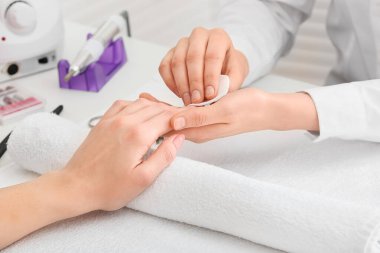 Manikür ustası kadın müşteriyle güzellik salonunda çalışıyor.