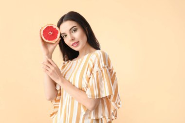 Arkaplanda greyfurt olan güzel bir genç kadın.