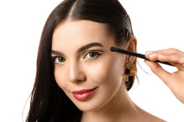 Güzel genç bir kadın beyaz arka plana makyaj yapıyor.