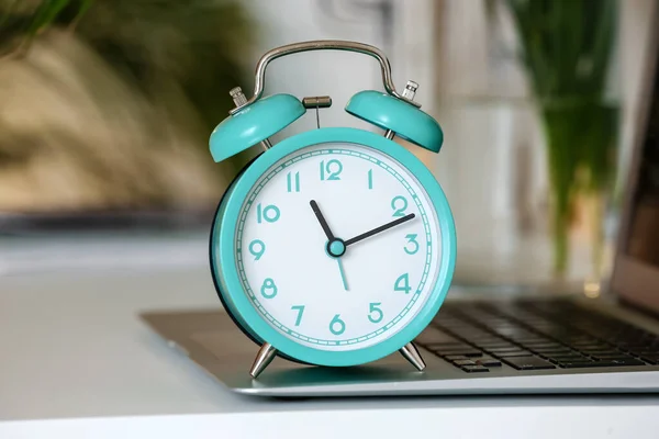 Alarm clock and laptop on table