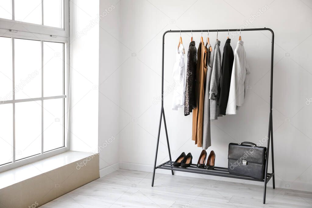 Rack with stylish clothes in room