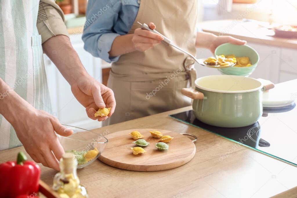 Young couple cooking tasty ravioli in kitchen