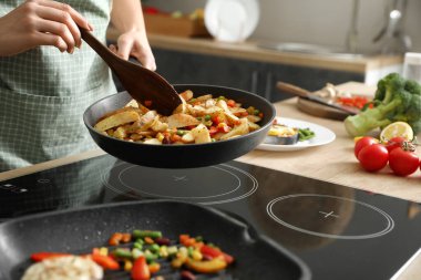 Mutfakta sebzeli patates kızartması yapan bir kadın.