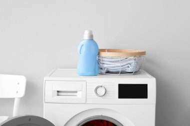 Deterjanı olan modern çamaşır makinesi ve ışık duvarının yanında çamaşır makinesi.