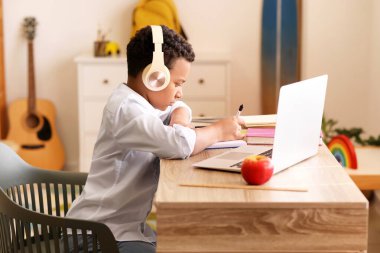 Küçük Afro-Amerikalı okul çocuğu evde online çalışıyor.
